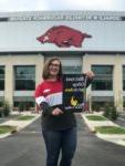 student holding BHC sign standing in front of a stadium