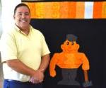 Kewanee High School teacher standing in front of a quilt featuring the school's mascot, 一个锅炉制造厂