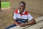 student sitting at a picnic table smiling