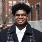 smiling male student with brick buildings in the background