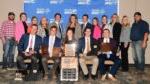 5 people seated with awards and 12 people standing