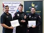 3 people with certificates & awards in front of banners