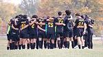 soccer players huddling on field with arms around each other